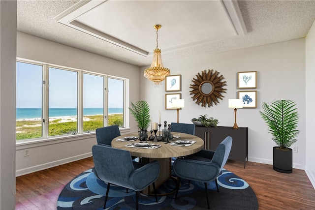 dining space with wood finished floors, baseboards, a water view, a textured ceiling, and a chandelier