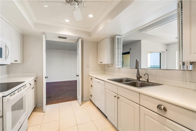 kitchen featuring white appliances, a sink, a tray ceiling, light countertops, and recessed lighting