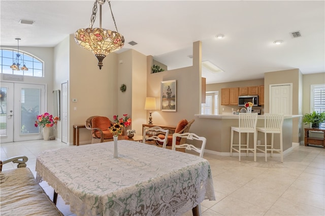 dining room with french doors, lofted ceiling, light tile patterned floors, and a chandelier