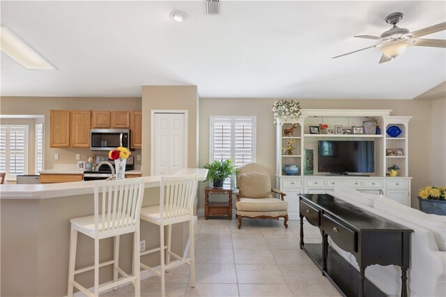 kitchen with a wealth of natural light, light brown cabinetry, appliances with stainless steel finishes, and light tile patterned floors