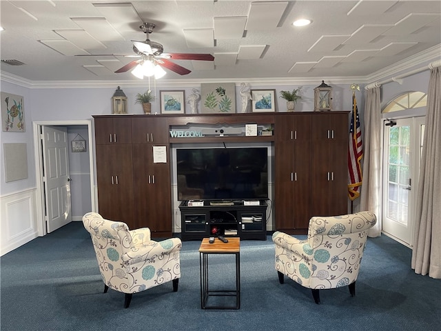 living room with ceiling fan, dark colored carpet, and ornamental molding