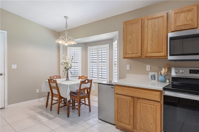 kitchen with appliances with stainless steel finishes, an inviting chandelier, light tile patterned floors, and hanging light fixtures