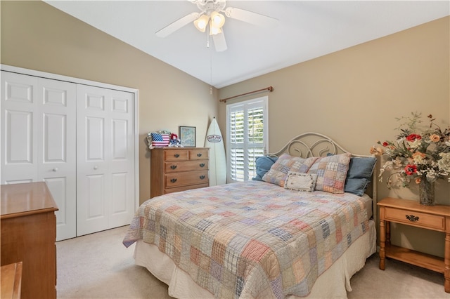 bedroom with ceiling fan, a closet, vaulted ceiling, and light colored carpet