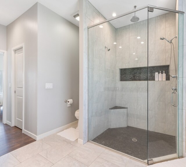 bathroom featuring tile patterned floors, toilet, and a shower with door