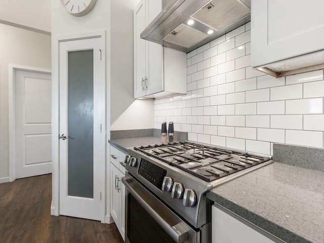 kitchen with white cabinetry, wall chimney range hood, stainless steel range with gas cooktop, and dark stone counters