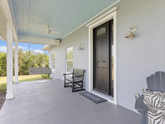 view of exterior entry with ceiling fan and a porch