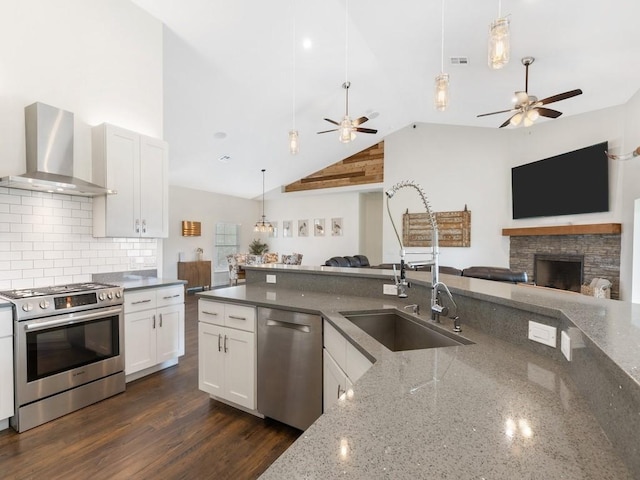 kitchen featuring appliances with stainless steel finishes, white cabinetry, backsplash, dark stone countertops, and wall chimney exhaust hood