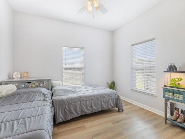 bedroom featuring ceiling fan, multiple windows, and light hardwood / wood-style flooring