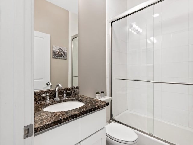 full bathroom featuring vanity, enclosed tub / shower combo, and toilet