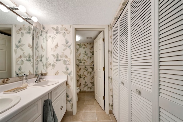 bathroom with tile patterned flooring, vanity, a textured ceiling, and toilet