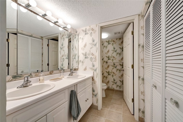 bathroom with tile patterned flooring, vanity, a textured ceiling, and toilet