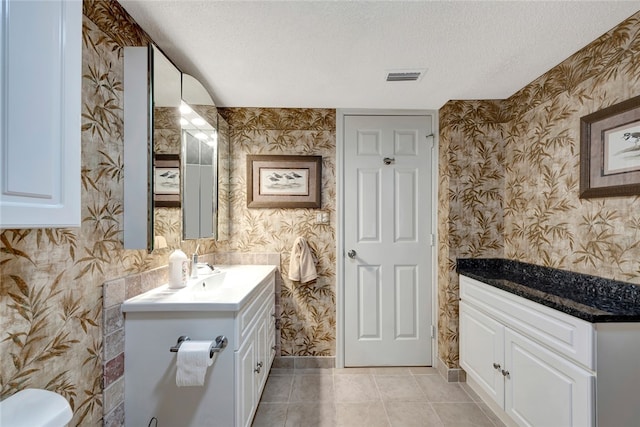 bathroom with tile patterned flooring, vanity, a textured ceiling, and toilet