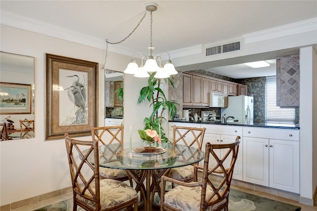 tiled dining area featuring a textured ceiling, an inviting chandelier, crown molding, and sink