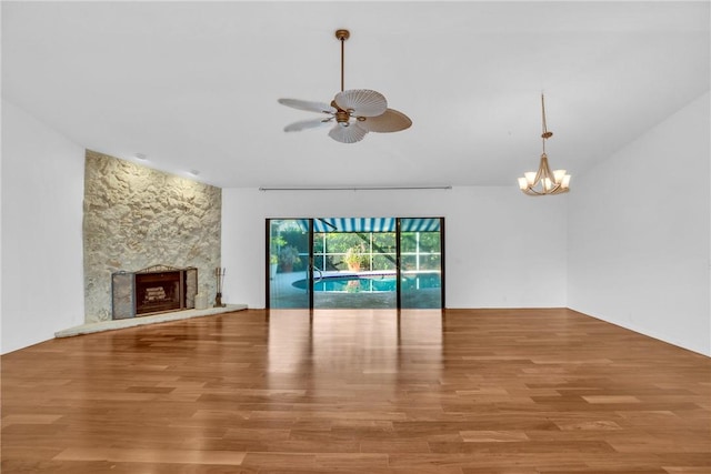 unfurnished living room featuring hardwood / wood-style flooring, vaulted ceiling, ceiling fan with notable chandelier, and a fireplace