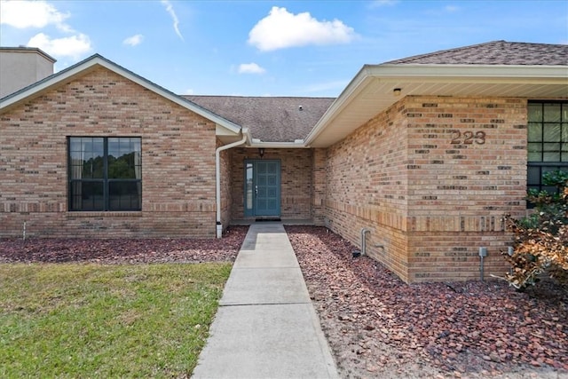 property entrance with brick siding and a shingled roof