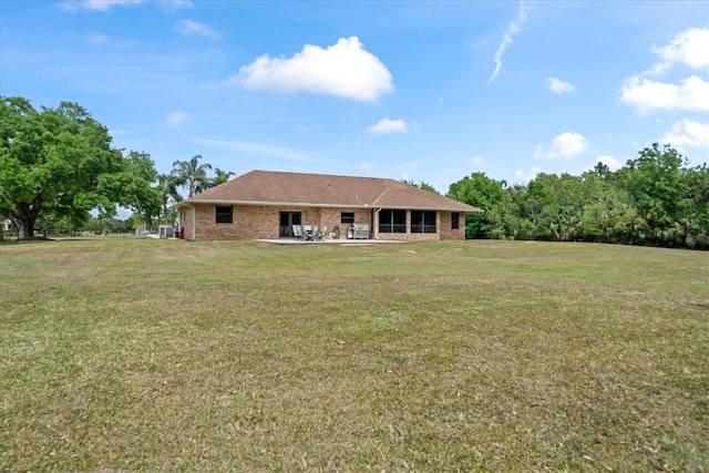 rear view of house featuring a patio area, brick siding, and a lawn