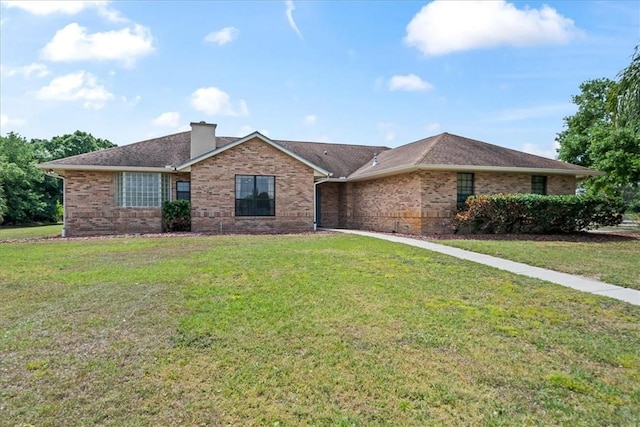 single story home with brick siding, a chimney, and a front lawn