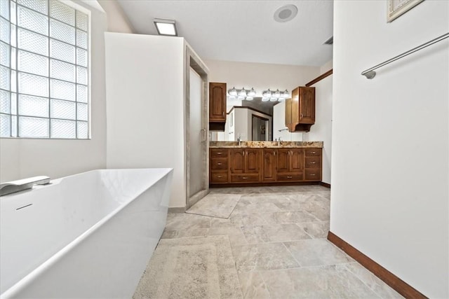 bathroom with a sink, a soaking tub, double vanity, and baseboards