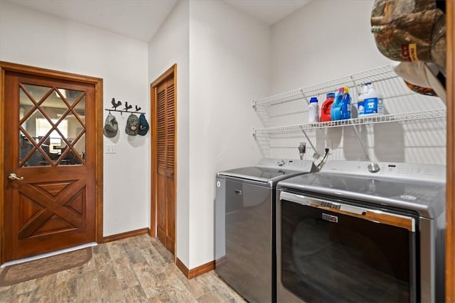 clothes washing area featuring light wood-style floors, baseboards, and washing machine and clothes dryer