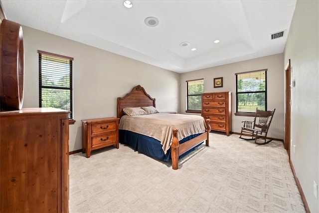 bedroom with baseboards, recessed lighting, visible vents, a tray ceiling, and light colored carpet