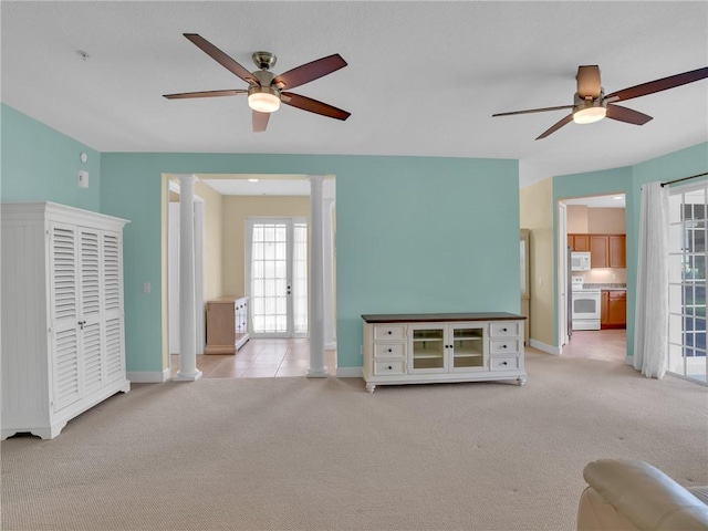 unfurnished living room with ornate columns, light carpet, and ceiling fan