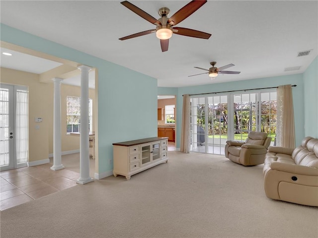 living room with ornate columns, ceiling fan, and light colored carpet