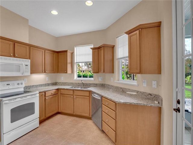 kitchen featuring sink, white appliances, a healthy amount of sunlight, and light stone countertops