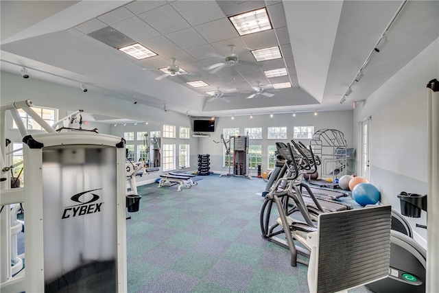 gym with ceiling fan and a raised ceiling