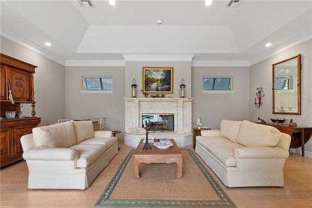 living room featuring light wood-type flooring, a fireplace, and a tray ceiling