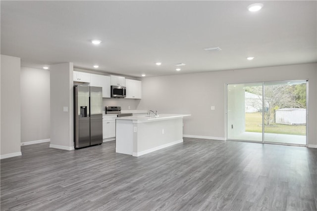901 Brickell St SE, Palm Bay, FL 32909 - kitchen with stainless steel appliances, open floor plan, wood finished floors, white cabinetry, and recessed lighting