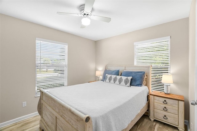 bedroom featuring light wood finished floors, multiple windows, and baseboards