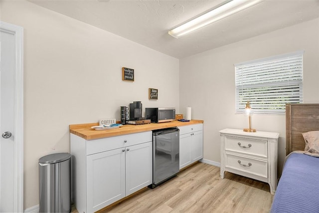 kitchen with white cabinetry, fridge, light wood-style flooring, and wooden counters