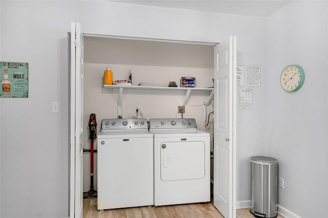 laundry room featuring baseboards, light wood finished floors, laundry area, and washer and clothes dryer