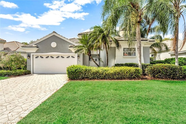 mediterranean / spanish home featuring a tiled roof, an attached garage, decorative driveway, a front lawn, and stucco siding