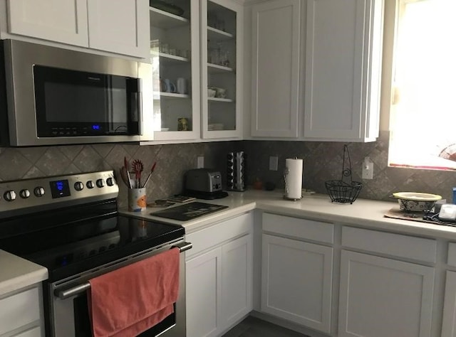 kitchen with white cabinets, backsplash, and stainless steel appliances