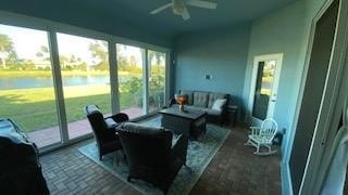 sunroom / solarium featuring ceiling fan, plenty of natural light, and a water view