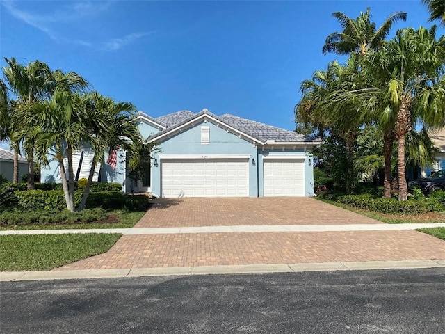 view of front of home featuring an attached garage, decorative driveway, and stucco siding