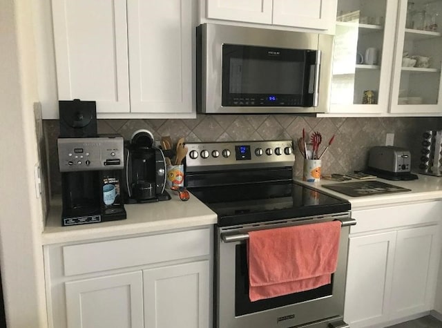 kitchen with backsplash, white cabinetry, and stainless steel appliances