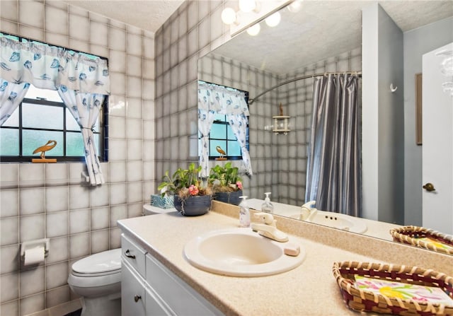 bathroom with walk in shower, a textured ceiling, vanity, toilet, and tile walls