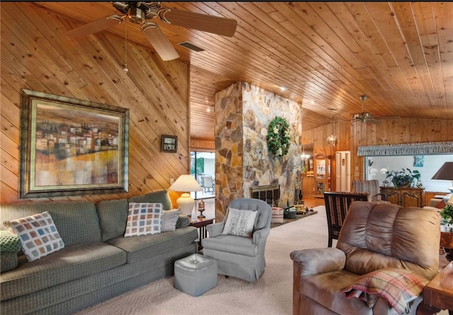 living room with a stone fireplace, wood ceiling, wooden walls, and carpet