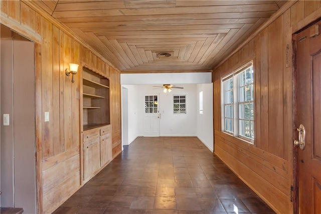 hall featuring ornamental molding, wooden ceiling, built in features, and wood walls