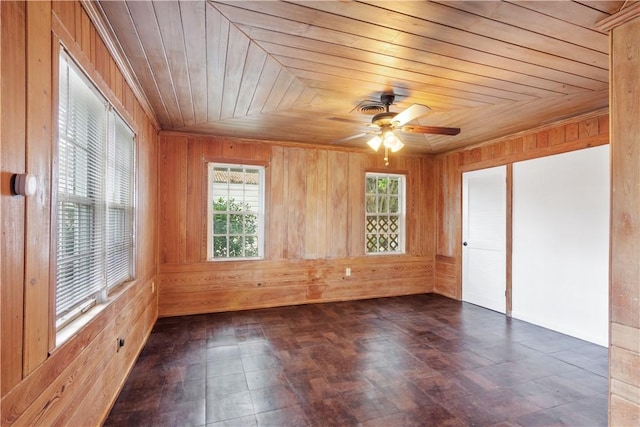 empty room featuring wooden ceiling, ceiling fan, and wood walls