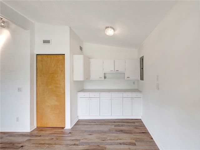 kitchen with white cabinetry, lofted ceiling, electric panel, and light hardwood / wood-style floors