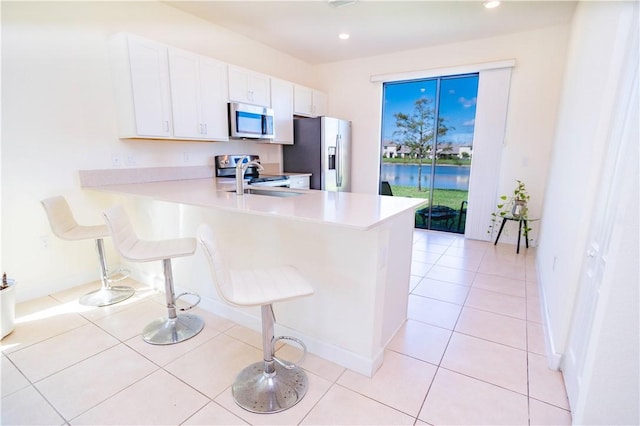 kitchen featuring sink, stainless steel appliances, kitchen peninsula, a breakfast bar area, and white cabinets