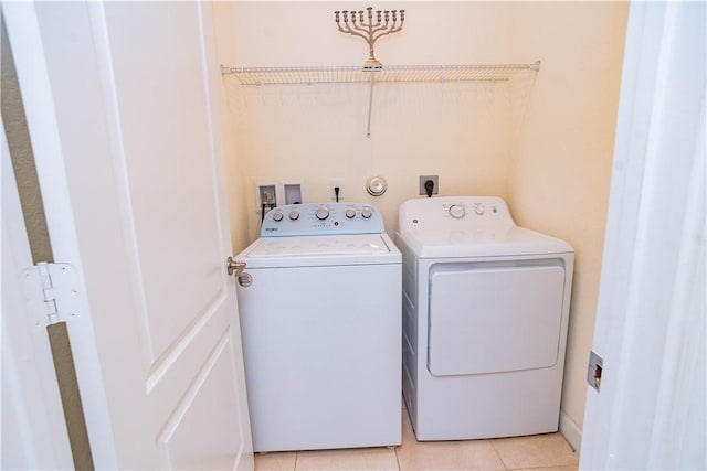 clothes washing area featuring light tile patterned flooring and washing machine and dryer