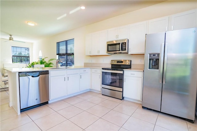 kitchen with kitchen peninsula, stainless steel appliances, white cabinets, and sink