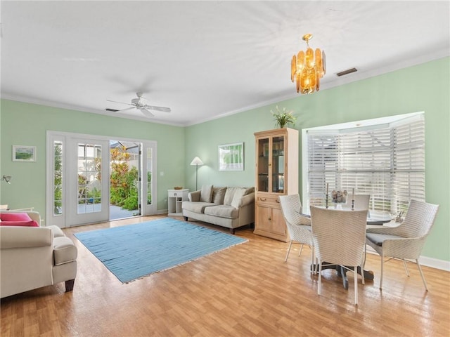 living room with ceiling fan with notable chandelier, light hardwood / wood-style floors, and crown molding