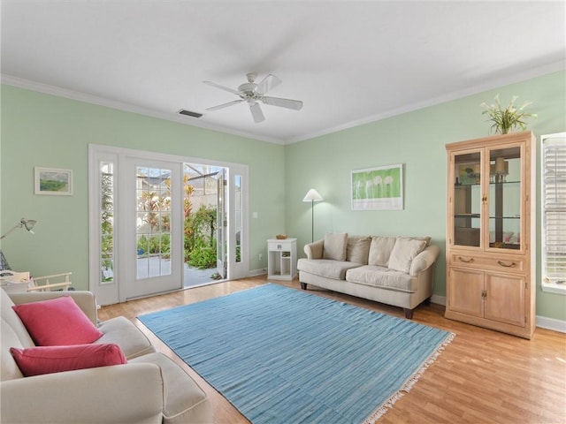 living room with light hardwood / wood-style floors, ceiling fan, and crown molding