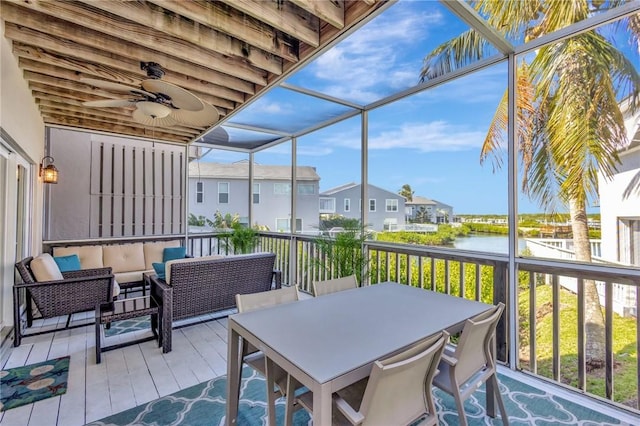 sunroom featuring a water view, a residential view, and a ceiling fan