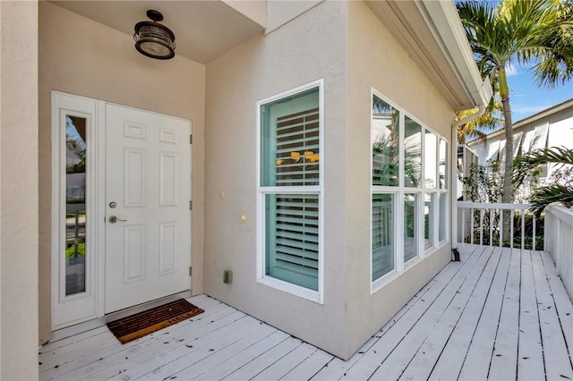 view of exterior entry with a deck and stucco siding